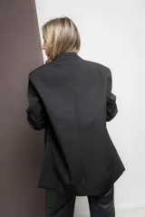Blazer negro de corte oversize con solapas de muesca, cierre frontal con dos botones y bolsillos de parche.