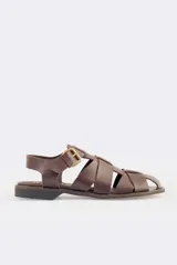 Sandalias bajas de cuero marrón con tiras entrecruzadas y hebilla dorada.