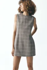 Vestido corto de Zara Woman Collection con estampado a cuadros en tonos grises, cuello redondo y sin mangas. Cierre trasero con cremallera oculta.