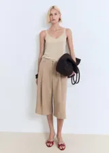 Top de punto fino color beige con brillo sutil, escote en V y tirantes finos.