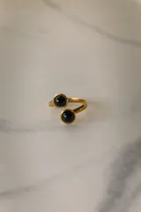 Anillo dorado ajustable de acero quirúrgico hipoalergénico con dos piedras redondas de color violeta.