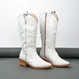 Bota texana de cuero vacuno negro con detalles bordados en dorado y plateado en la caña. Tiene taco de madera con folia de cuero de 5cm, entre suela de goma de 1cm, inclinación de horma de 4cm, altura de caña de 31cm y cierre YKK del lado interno. La horma es de punta fina, ancha y cómoda.