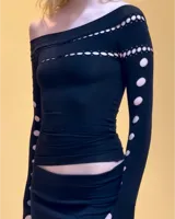 Remera negra de mangas largas con escote asimétrico y aberturas circulares.