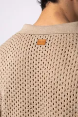 Camisa negra tejida de manga corta, con calado aireado, cuello tipo bowling y botones al tono. Diseño de corte relajado.