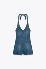 Mono corto de denim azul, con cuello halter que se ata al cuello, escote en V y espalda descubierta. Cierre lateral con cremallera metálica.