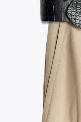 Vestido midi con cuerpo negro sin mangas y falda plisada color beige. Incluye cinturón negro con hebilla rectangular.