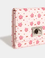 Billetera de cuerina color crema con estampado de pequeñas rosas rosadas, con broche metálico plateado y compartimentos para tarjetas.
