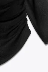 Top negro de escote asimétrico con una manga corta y una manga larga. Tiene detalle de frunces laterales y bajo asimétrico.