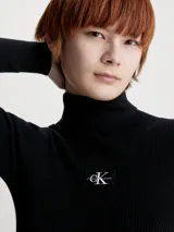 Vestido corto negro de punto acanalado, con cuello alto y mangas largas. Presenta logo de Calvin Klein bordado en el pecho.