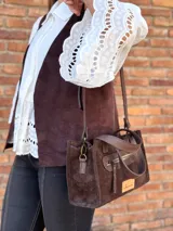 Cartera bandolera de cuero color marrón chocolate, con forro de tela y herrajes dorados. Tiene doble asa de mano y correa larga regulable y desmontable. Incluye bolsillo frontal con cierre y bolsillo interno.