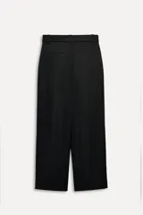 Pantalón negro de tiro alto con trabillas, bolsillos laterales y falsos bolsillos de vivo en la espalda. Incluye cinturón lazada en el mismo tejido.