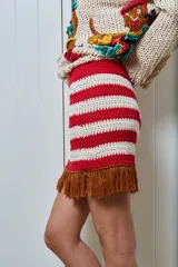 Minifalda tejida a mano en hilado de algodón, con diseño a rayas horizontales en color amarillo y blanco. Presenta flecos marrones en el ruedo.