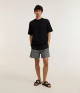 Bermuda de baño masculina confeccionada en microfibra gris con cintura elástica ajustable con cordón, bolsillos laterales y bolsillo trasero con cierre. Presenta estampado bicolor en la parte inferior.