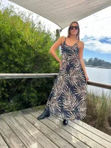 Vestido largo de tirantes con estampado de hojas en tonos marrones y celestes sobre fondo negro.