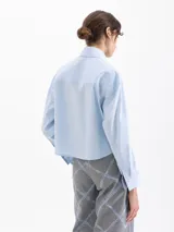 Camisa blanca de manga larga con cuello clásico y botones de diferentes colores.