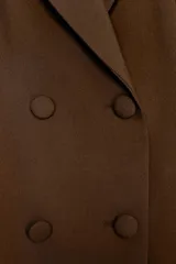 Blazer marrón de cuello solapa y manga larga. Bolsillos con solapa en delantero y cierre frontal cruzado con botones forrados.