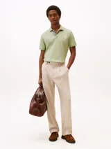 Chomba verde claro de corte regular, confeccionada en tejido piqué de algodón orgánico con un toque de elastano. Tiene cuello tipo chomba, cartera de dos botones y logo de Tommy Hilfiger bordado en el pecho.