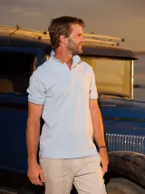 Remera tipo polo color beige, de corte clásico, con cuello y puños acanalados en contraste marrón oscuro.