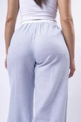Pantalón de tela a rayas verticales celestes y blancas, con corte amplio, cintura elástica y cordón ajustable.