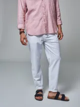 Pantalón color beige de corte regular fit, confeccionado en lino. Cuenta con dos bolsillos frontales y dos bolsillos posteriores, bajo con botamanga y presilla, aplique de badana.