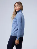 Polera de punto fino marca Nienty, color blanco, con cuello alto volcado y mangas largas con detalle de tajo en los puños.