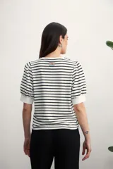 Remera de manga corta con cuello redondo y estampado de rayas horizontales blancas y negras. Mangas abullonadas con puño blanco.