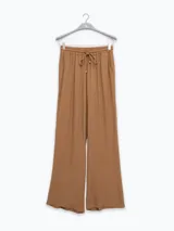 Pantalón palazzo negro de crepe con cintura elastizada, bolsillos laterales y terminaciones con logo en cobre.