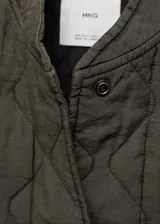 Chaqueta acolchada color verde militar con cuello perkins, cierre frontal con botones, dos bolsillos laterales y detalle fruncido en el bajo. Estilo bomber.