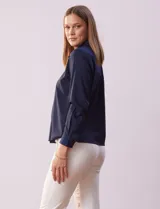 Camisa blanca de gasa, marca Sioni, con cuello con solapa, abertura central con botones y mangas largas con puño y botón.