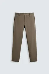 Pantalón de vestir color marrón, de corte slim fit, confeccionado en tejido elástico. Presenta bolsillos frontales y traseros de vivo con botón.