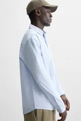 Camisa azul marino de corte regular fit, confeccionada en tejido de algodón Oxford. Tiene cuello abotonado, manga larga con puños abotonados, bolsillo de parche en el pecho y cierre frontal con botones.