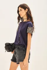 Remera de jersey 100% algodón color blanco, con cuello redondo y manga corta caída. Las mangas están completamente bordadas con lentejuelas tono sobre tono.