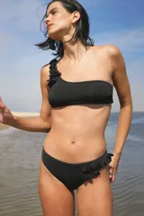 Conjunto de bikini negro con corpiño de un solo hombro con volados y bombacha clásica con volados en los laterales.