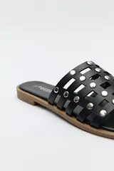 Sandalia baja negra con diseño entrelazado y apliques metálicos.