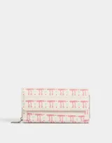 Billetera tipo fichero con estampado de moños rosas y celestes sobre fondo blanco. Tiene cierre superior y solapa con broche.