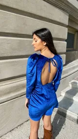 Vestido corto fucsia de terciopelo, con mangas largas abullonadas y falda drapeada.