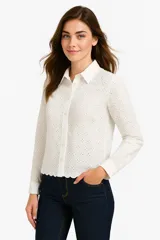 Camisa blanca de algodón con broderie, corte holgado, cuello camisero y cierre frontal con botones.
