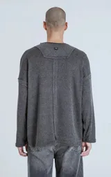 Sweater gris oscuro de manga larga con cuello redondo y paneles laterales con costuras a la vista.