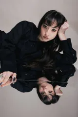 Vestido corto negro estilo camisero con botones frontales, mangas largas y lazos laterales ajustables.