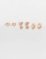 Set de tres pares de aros bañados en oro rosa: aros pasantes con forma de corazón, aros colgantes con forma de mariposa con strass y aros tipo argolla con textura. Todos con cierre a presión.