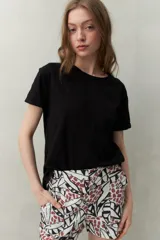 Remera negra de manga corta confeccionada en algodón liviano con textura levemente jaspeada. Presenta tajos laterales y costura central al frente.