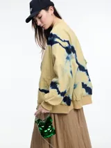 Campera bomber verde con estampado tie-dye en azul marino, cierre frontal y puños y cintura elastizados.