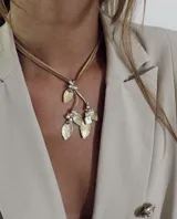Collar con colgante de hojas doradas y perlas, con cordón de cuero marrón.