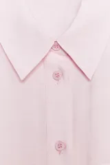 Camisa rosa claro confeccionada en hilatura con modal, de corte holgado, con cuello solapa, manga larga terminada en puño, dos bolsillos con solapa en el delantero y cierre frontal con botones.