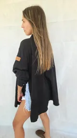 Camisa negra de corte amplio, con mangas largas y puños abotonados.