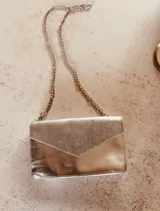 Cartera de fiesta plateada con solapa texturizada y cadena metálica.