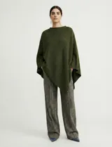 Poncho tejido de punto grueso, color mostaza/mostaza oscuro, con cuello redondo y caída amplia.