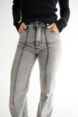 Pantalón de jean gris de corte acampanado, con tiro alto y costuras verticales al frente.