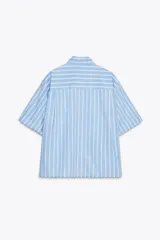 Camisa celeste con rayas verticales blancas, de corte holgado, cuello solapa, manga corta con dobladillo y bolsillo de parche en el pecho.
