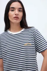Remera de algodón a rayas horizontales blancas y azul marino, con cuello redondo y bordado dorado en el pecho.